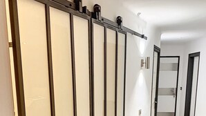 Un pasillo con puerta corredera, piso de madera y una puerta que da a otra habitación.