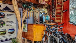 A rustic inn with a wooden interior, bicycles, and a signboard detailing amenities like camping, dormitory, and bicycle tours. - Starlight Mountain Lodge (Sigchos)