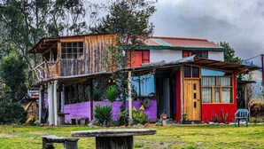 A rustic wooden house with a balcony, a small porch, and a front door. - Starlight Mountain Lodge (Sigchos)