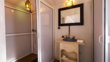 Un baño pequeño con espejo, lavamanos y estante.