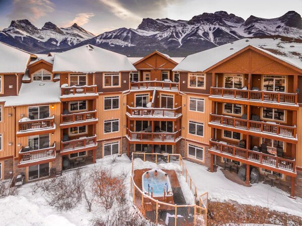 Ein mehrstöckiges Lodgegebäude mit Balkonen, einem zentralen Innenhof und Blick auf schneebedeckte Berge.