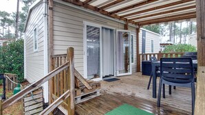 Eine kleine Holzhütte mit einer Holzterrasse, einer Veranda und einer Schiebetür.