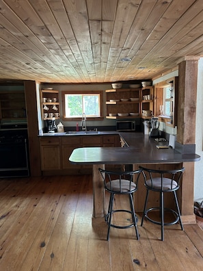 A wooden kitchen with a central island, bar stools, and built-in shelves. - Northwoods Retreat in Beautiful Ely, Minnesota (Ely)