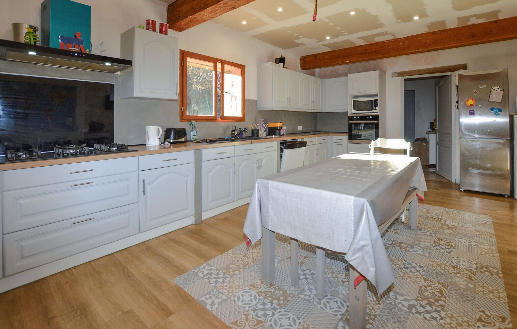A modern kitchen with white cabinetry, a dining table, and a built-in oven.