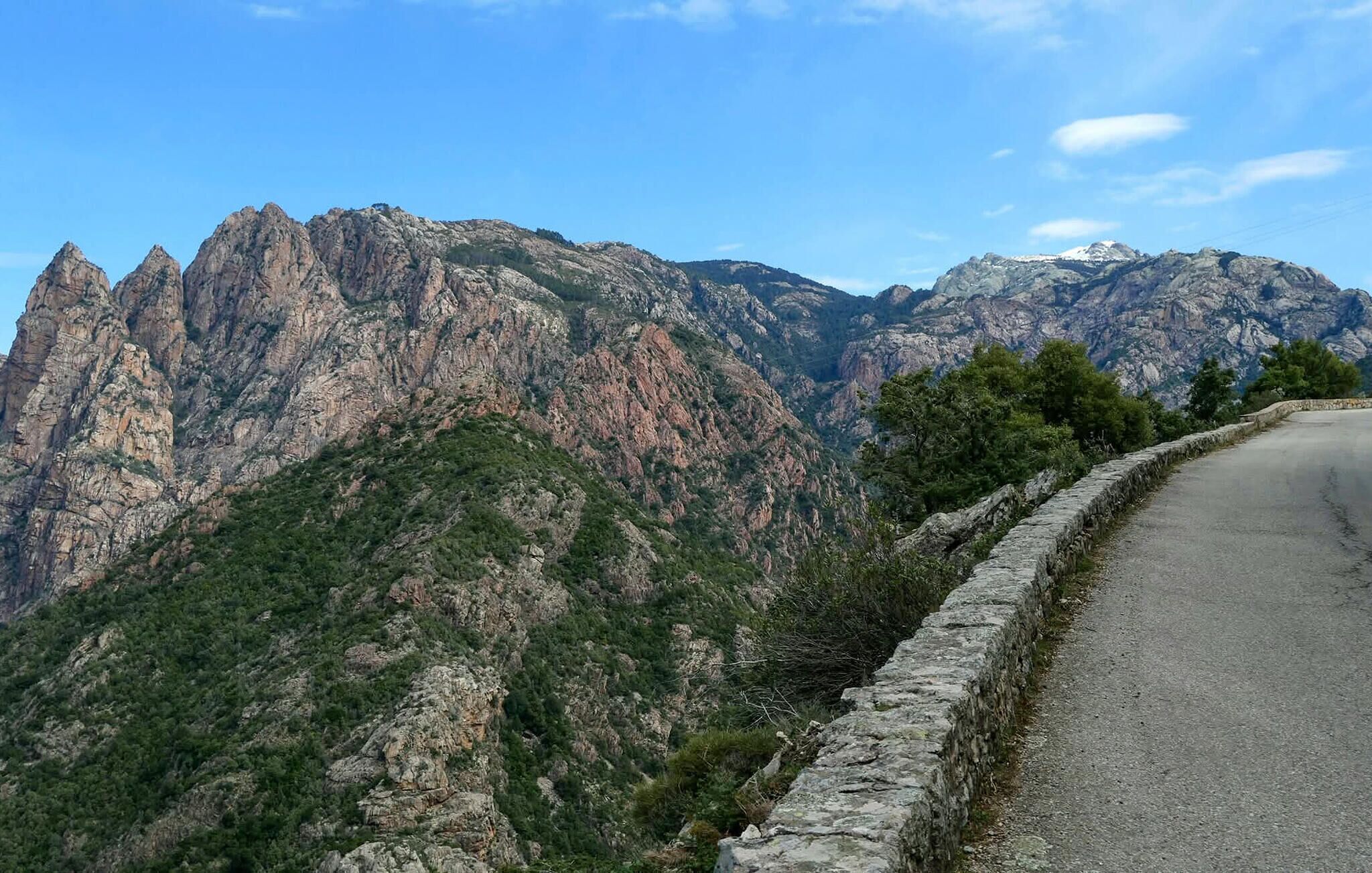 Un paysage montagneux, avec une route goudronnée qui serpente le long de la pente.