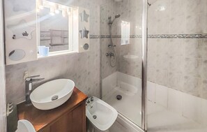 A modern bathroom with a glass-enclosed shower, a double sink vanity, and a mirror with decorative elements. - Cozy apartment in Agde with house sea view (Agde)