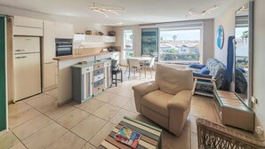 A modern kitchen with a dining area, a sofa, and a view of the city. - Cozy apartment in Agde with house sea view (Agde)