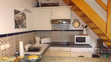 Een koelkast, een microgolfoven, kookgerei, borden en bestek