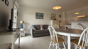 A modern kitchen with a dining table, chairs, and a grey sofa.