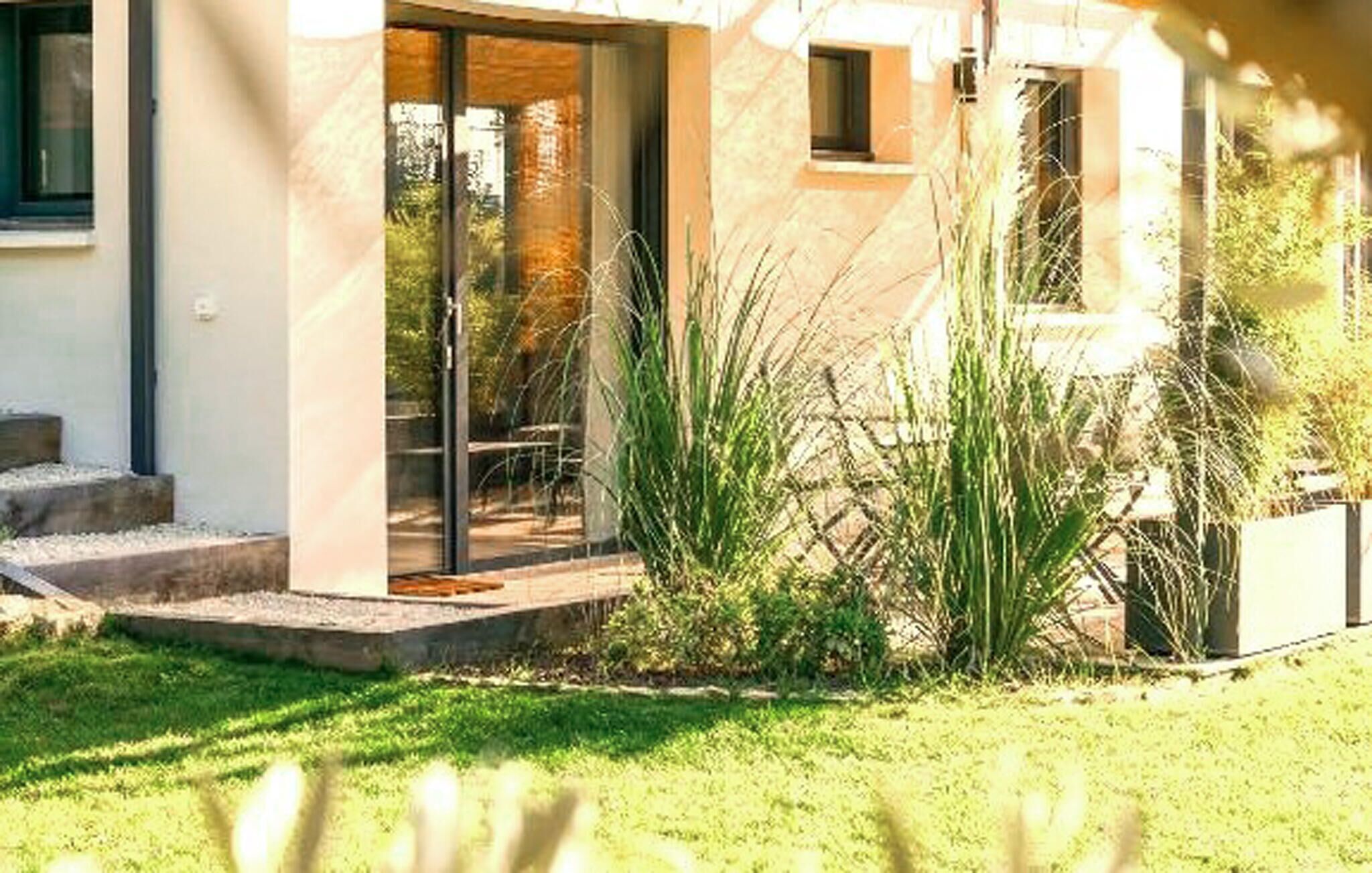 A modern house with a glass door leading to a patio area.