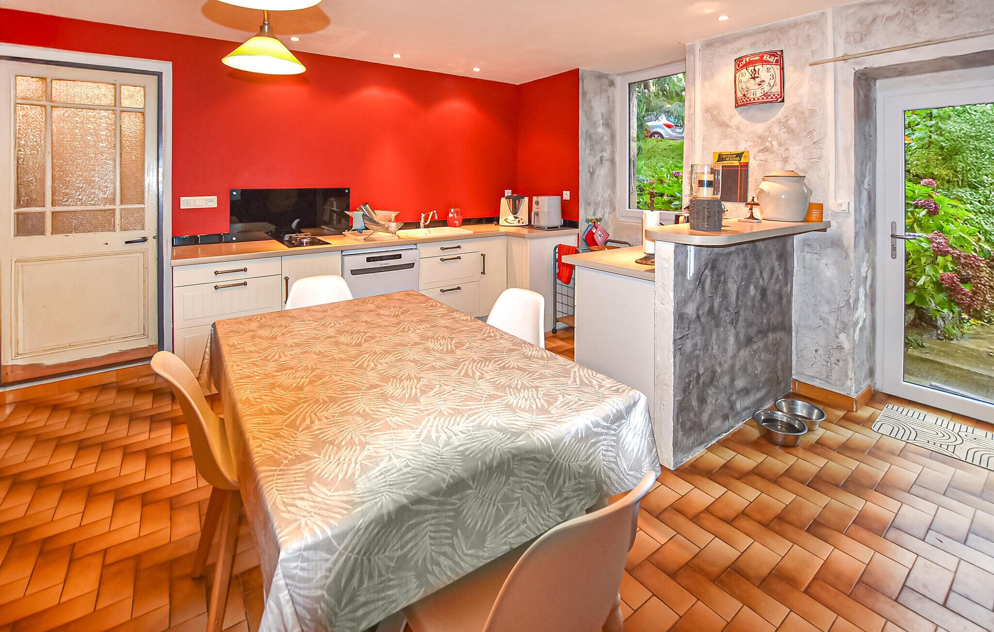 A compact kitchen with a dining area, a coffee bar, and a view of greenery outside.