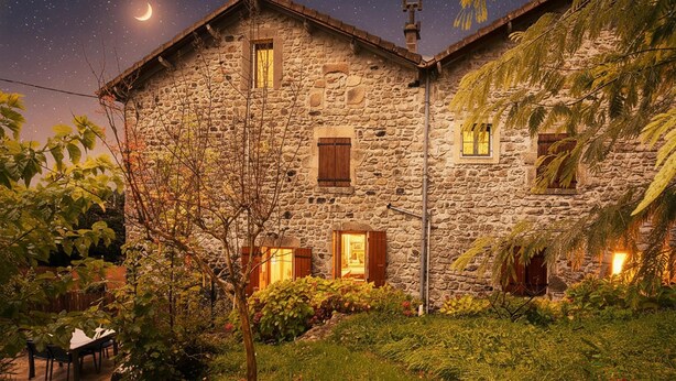 Un edificio in pietra con molte finestre, un giardino con piante e un tavolo, e un cielo notturno con stelle e una luna crescente.