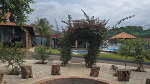 A courtyard with a circular brick fire pit, surrounded by stone slabs and wooden posts. - BomjaMinas property, swimming pool, bed linens and towels, 17 km from Inhotim. (Mário Campos)