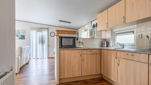 A modern kitchen with wooden cabinets, a microwave, a kettle, and a window with a view. - Beautiful home in Erm with WiFi (Erm)