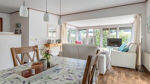A well-lit living room with a dining area, a sofa, a TV, and large windows offering a view of the outdoors. - Beautiful home in Erm with WiFi (Erm)