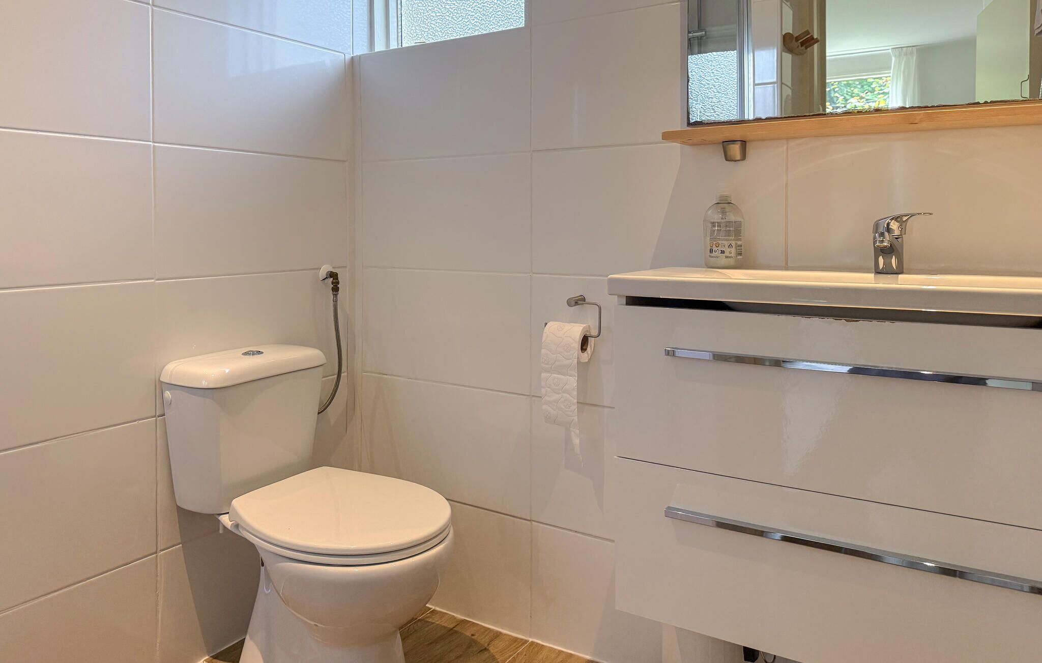 Une salle de bain moderne équipée de toilettes, d’une douche et d’un lavabo avec un miroir au-dessus.
