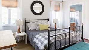 Quarto com cama, mesas de cabeceira, escrivaninha e uma cadeira.