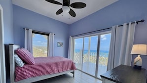 A bedroom with a bed, a desk, a ceiling fan, and a view of the beach. - Spacious 6-bedroom villa with AC and large private pool (Christiansted)