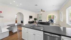 A modern kitchen with white cabinets, a black countertop, and stainless steel appliances. - 🏖️ 4BR Beach House w/ Heated Spa and Pool (Naples)