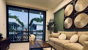 En stue med sofa, sofabord og udsigt til en balkon med havemøbler.