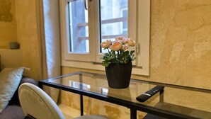 A potted plant with flowers on a glass table in a room with a sofa and a window. - Studio Tourny, 2 pers, centre Bordeaux (BORDEAUX)