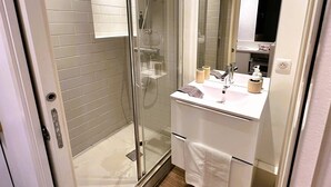 A bathroom with a glass shower enclosure, a white sink with a mirror, and a towel rack. - Studio Tourny, 2 pers, centre Bordeaux (BORDEAUX)