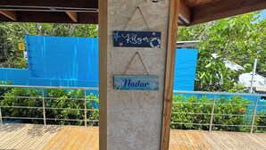 Una terraza de madera con dos letreros colgando de un pilar, uno dice "Kelizjar" y el otro "Nadar".