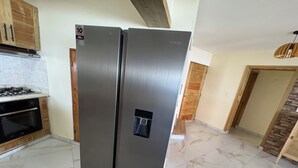 Una cocina con refrigerador de acero inoxidable, estufa y gabinetes de madera.