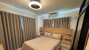 Un dormitorio moderno con una cama grande, cabecera de madera, mesitas de noche y un ventilador de techo.
