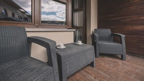 Un balcón con mobiliario de mimbre, vista al cielo y pared de madera.