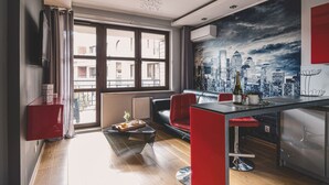 Una sala de estar moderna con un mural de paisaje urbano, una zona de comedor con barra y un armario rojo.