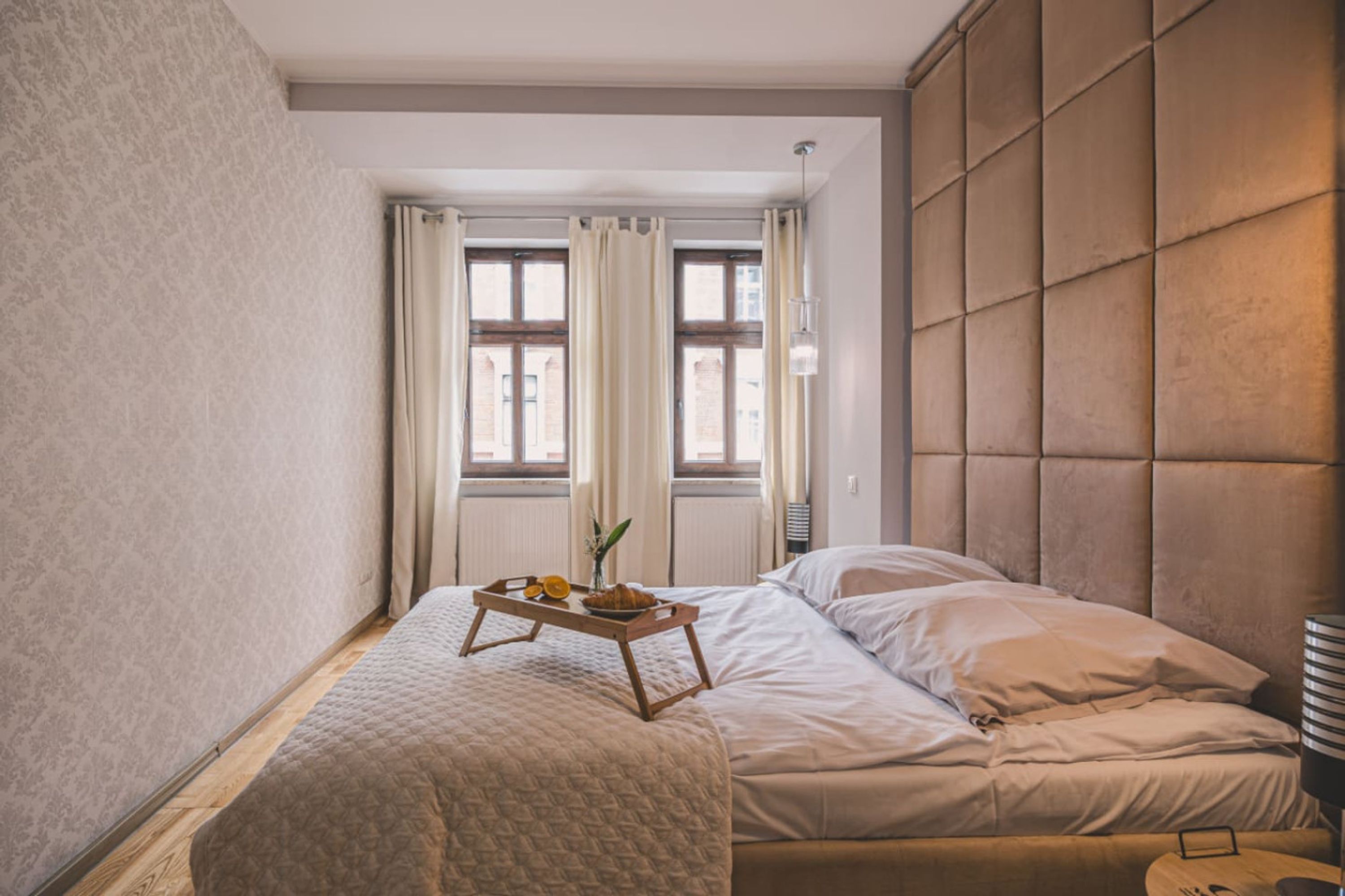 Ein Schlafzimmer mit einem Bett, einem Nachttisch mit einem Tablett Essen und einem Fenster mit Vorhängen.