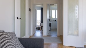Un couloir mène à une cuisine et à un coin repas, où se trouvent un canapé et un fauteuil.