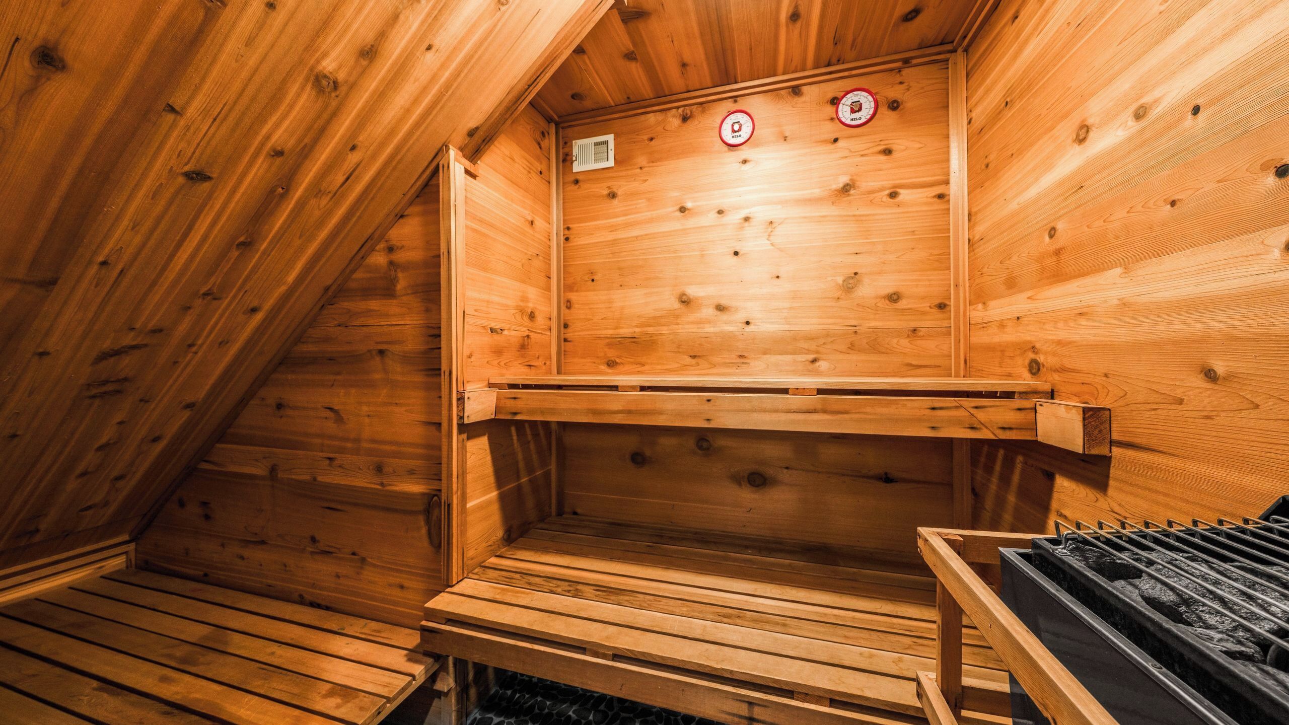 A wooden sauna with benches, a bench heater, and a ventilation system.