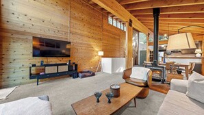 Interior acogedor de una cabaña con detalles de madera, una chimenea, un televisor y un espacio de descanso confortable.