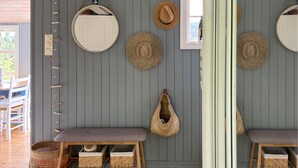 Een kamer met een houten bankje, een rieten mand en een hangende hoed.