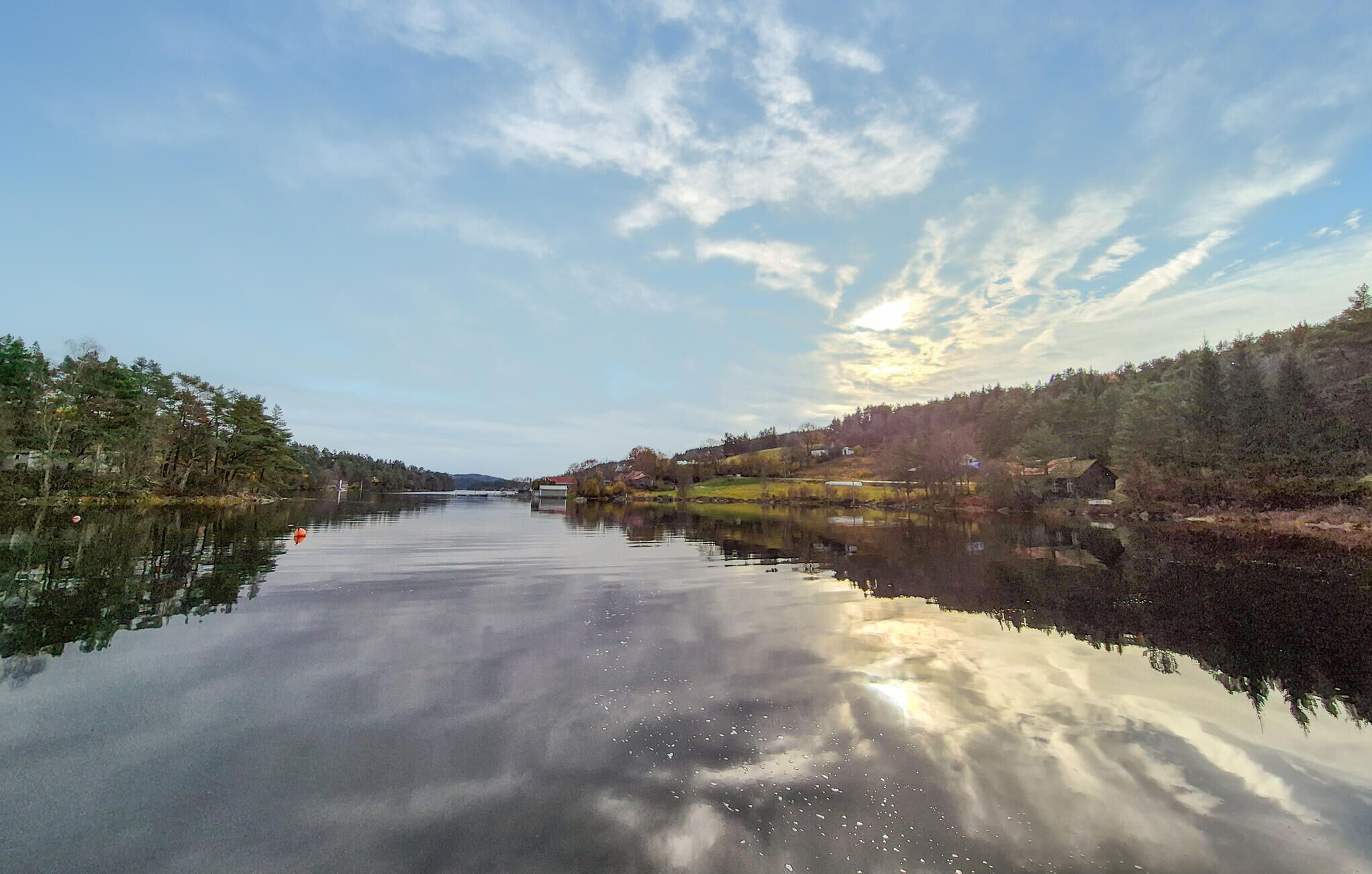 A calm river with reflections of trees and a clear sky.