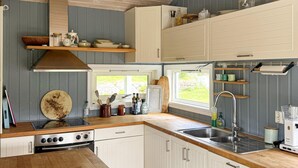 Een keuken met houten aanrecht, een fornuis, een spoelbak en witte kasten.