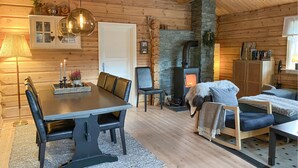 Een knus chaletinterieur met een eettafel, stoelen, een open haard en een bank.
