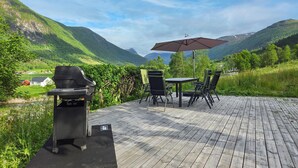 A patio with a grill, outdoor table, chairs, and an umbrella.