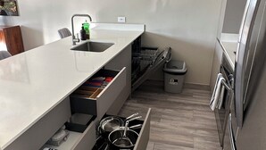 Une cuisine moderne avec des meubles blancs, un évier encastré et un réfrigérateur en acier inoxydable.