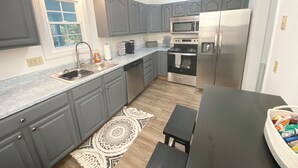 A kitchen with grey cabinets, a stainless steel refrigerator, a microwave, and a stove. - High End Downtown 2-Bed Loft, Pet & Child Friendly (Roanoke)