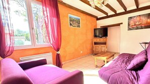 A living room with a sofa, a television, and a table. - La Devèze - LIMOUX - Gîte (LIMOUX)