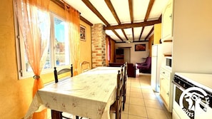 A dining area with a table, chairs, and a kitchen with a refrigerator and stove. - La Devèze - LIMOUX - Gîte (LIMOUX)