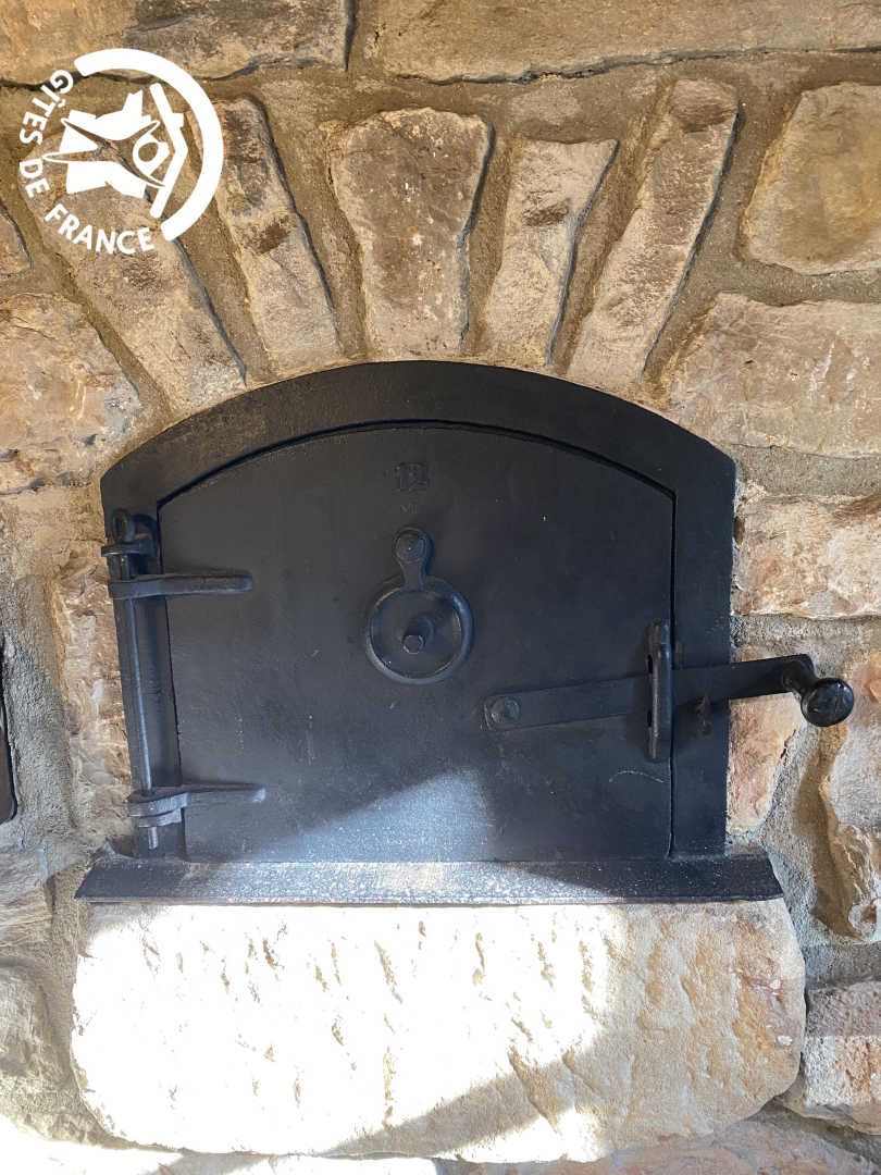 Une cheminée en pierre avec une porte en métal noir, intégrée dans un mur en pierre rustique.