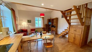 Un coin repas avec une table et des chaises en bois, un escalier et une bibliothèque.