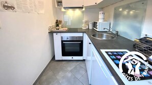 Una cocina moderna con armarios blancos, horno empotrado, cafetera y una tableta digital sobre la encimera.