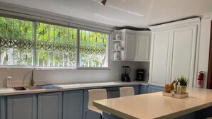 Una cocina con un ventanal grande, armarios blancos y una isla central.