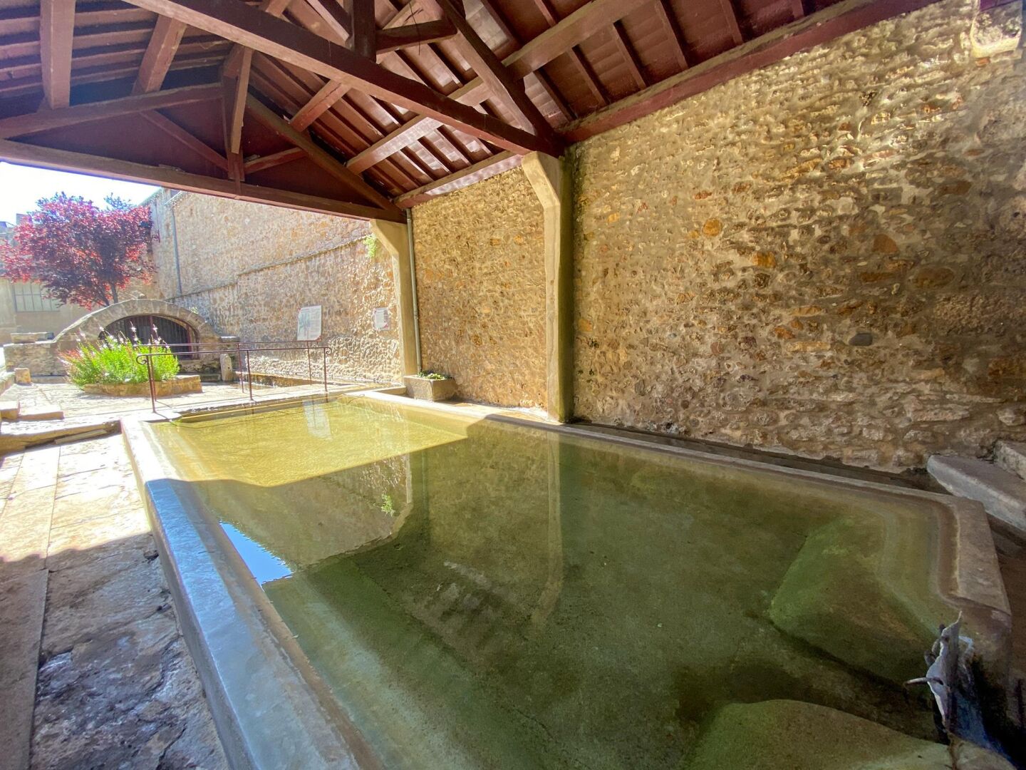 Un área de piscina con paredes de piedra, techo de madera y suelo de piedra.