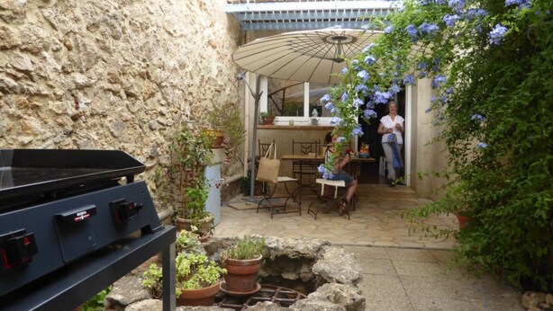 A stone-walled courtyard with a grill, potted plants, and a covered patio area. - Le Faubourg - FERRALS LES CORBIERES (FERRALS LES CORBIERES)